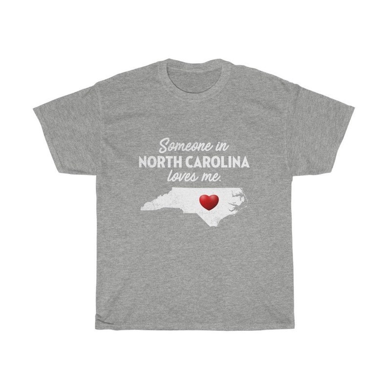 May include: Gray t-shirt with the text "Someone in NORTH CAROLINA loves me." and a red heart over an outline of the state of North Carolina.
