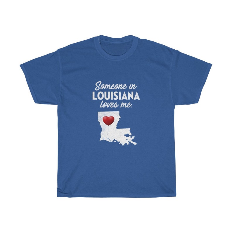 May include: Blue t-shirt with white text that reads "Someone in Louisiana loves me."  A white outline of the state of Louisiana with a red heart in the center is below the text.