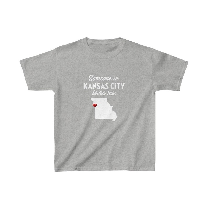 May include: Gray t-shirt with the text "Someone in KANSAS CITY loves me." and a white outline of the state of Missouri with a red heart over Kansas City.