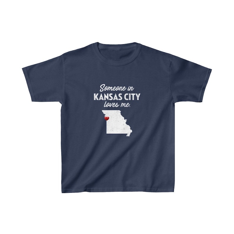May include: Navy blue t-shirt with a white outline of the state of Missouri and the text "Someone in Kansas City loves me." A red heart is placed over Kansas City.