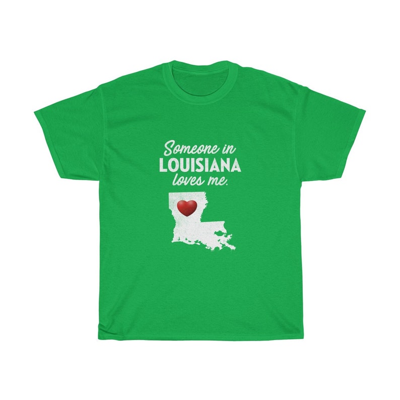 May include: Green t-shirt with white text that reads "Someone in Louisiana loves me."  A white outline of the state of Louisiana with a red heart in the center is below the text.