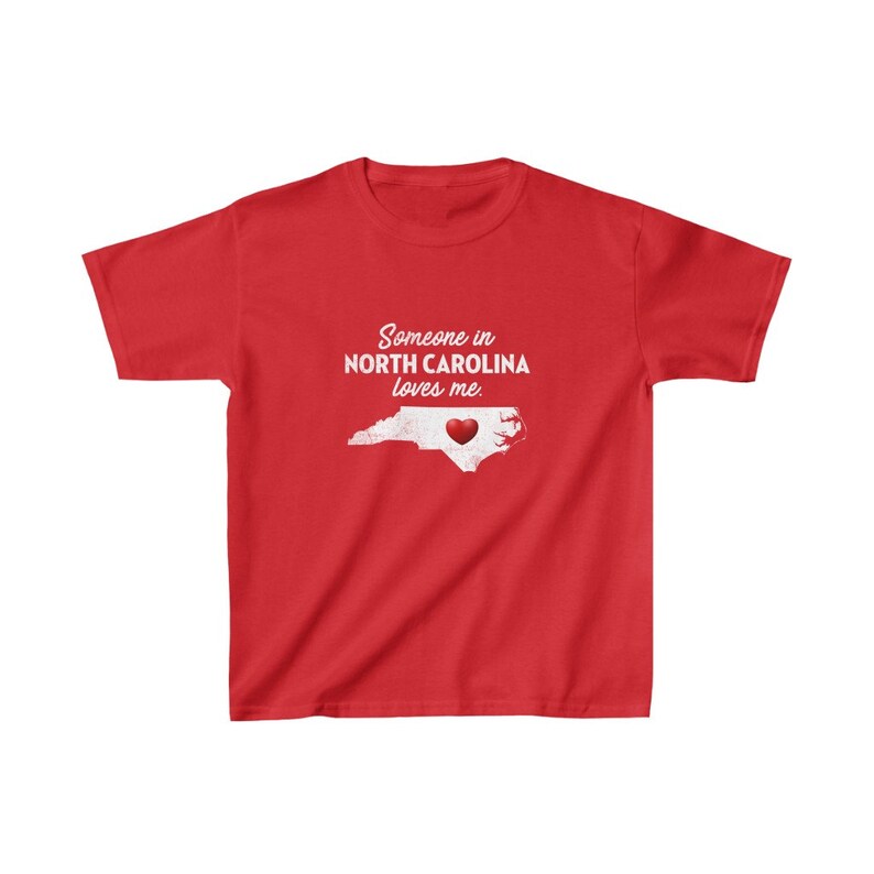 K&ouml;nnte beinhalten: Rotes T-Shirt mit einer wei&szlig;en Umrandung von North Carolina und einem roten Herzen in der Mitte. Der Text "Jemand in North Carolina liebt mich." ist auf das T-Shirt gedruckt.