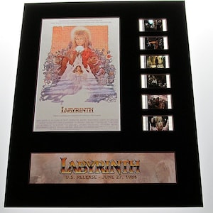 May include: A framed movie poster for the film Labyrinth, featuring a fantasy scene with a young girl and a goblin king. The poster includes a title card with the film's title and release date: "LABYRINTH U.S. RELEASE - JUNE 27, 1986". The poster is accompanied by six film strips from the movie.
