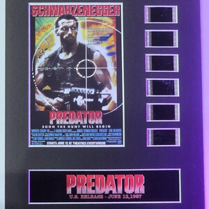 May include: A movie poster for the film "Predator" starring Arnold Schwarzenegger. The poster features a close-up of Schwarzenegger's face with a jungle background. The text "Predator" is in large, bold letters at the bottom of the poster. The poster also includes the text "Soon the hunt will begin" and "Starts June 12 at theatres everywhere".