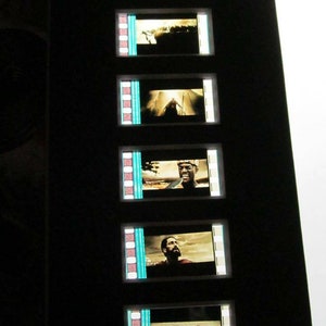 May include: A framed set of film strips with scenes from a movie. The film strips are black and white with a blue border. The scenes show a man in a dark suit, a man in a white shirt, and a man in a dark shirt.