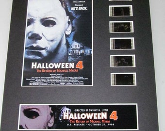 Peut inclure: Une affiche de film encadrée pour Halloween 4 : Le Retour de Michael Myers. L'affiche présente un gros plan du masque de Michael Myers et le texte "Il y a dix ans, il a changé le visage d'Halloween. Ce soir, il est de retour." L'affiche est entourée de six bandes de film du film.