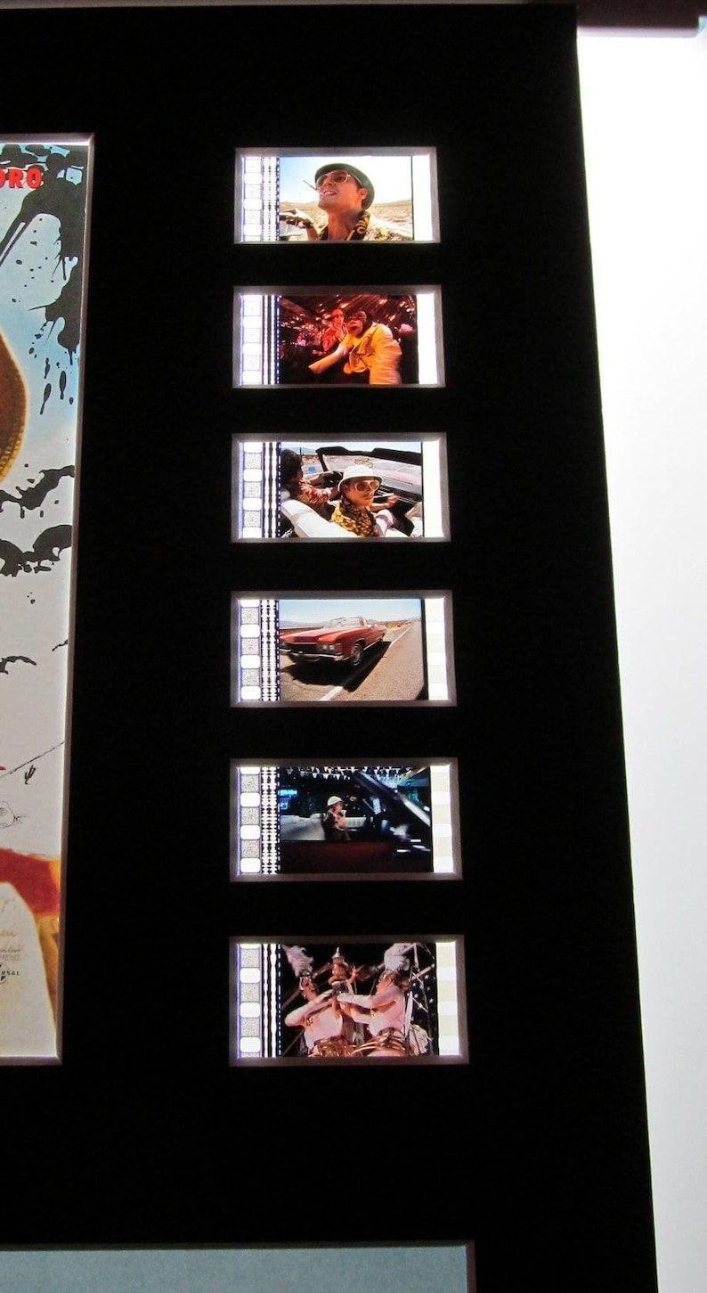 May include: A set of film strips featuring scenes from a movie. The strips are framed and displayed on a black background. The scenes include a man in a hat, a car driving down a road, and a group of people.