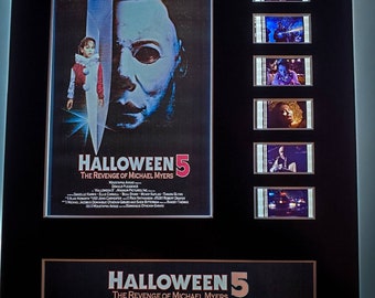 Peut inclure: Une affiche de film encadrée pour Halloween 5 : La Revanche de Michael Myers. L'affiche présente un gros plan du masque de Michael Myers et d'un couteau. L'affiche comprend également le titre du film, le slogan "Michael lives. And this time they're ready!" et la date de sortie "US Premiere - October 13, 1989".