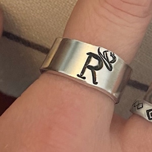 May include: A silver ring with the letter "R" engraved on it.