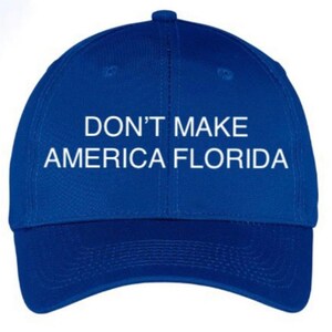 May include: A royal blue baseball cap with white embroidered text that reads "DON'T MAKE AMERICA FLORIDA".