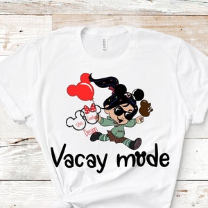 May include: White t-shirt with a cartoon character wearing sunglasses and holding a Mickey Mouse balloon and a Mickey Mouse ice cream. The text "Vacay mode" is printed below the character.