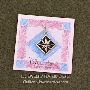 May include: A silver charm in the shape of a diamond with a compass star design. The charm is on a white card with a blue and pink background. The card says "Peter Jon Sterling Silver" and "© JEWELRY FOR QUILTERS QuiltersJewelry.etsy.com".