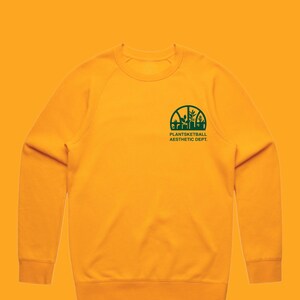 May include: A yellow sweatshirt with a green graphic of a basketball with plants growing out of it. The text "Plantsketball Aesthetic Dept." is below the graphic.