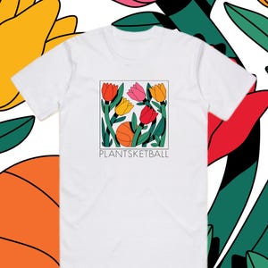 Könnte beinhalten: Weißes T-Shirt mit einem quadratischen Aufdruck von bunten Tulpen und einem Basketball. Die Tulpen sind rot, rosa und gelb mit grünen Stielen und Blättern. Der Text "PLANTSKETBALL" steht darunter. Der Hintergrund hat ein Blumenmuster.