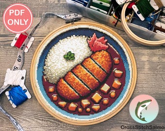 May include: A cross stitch pattern of a Japanese dish with rice, breaded pork cutlet, and a brown sauce. The pattern is in a wooden embroidery hoop on a wooden table. The pattern is from CrossStitchSalmon.