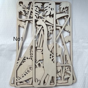 May include: A set of three wooden laser cut panels featuring a dinosaur and jungle foliage. The panels are layered to create a 3D effect. The text "No1" is visible on the left side of the image.
