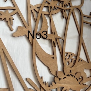 May include: A wooden wall decor with a floral design. The design features intricate cutouts of flowers and leaves. The piece is labeled "No3".