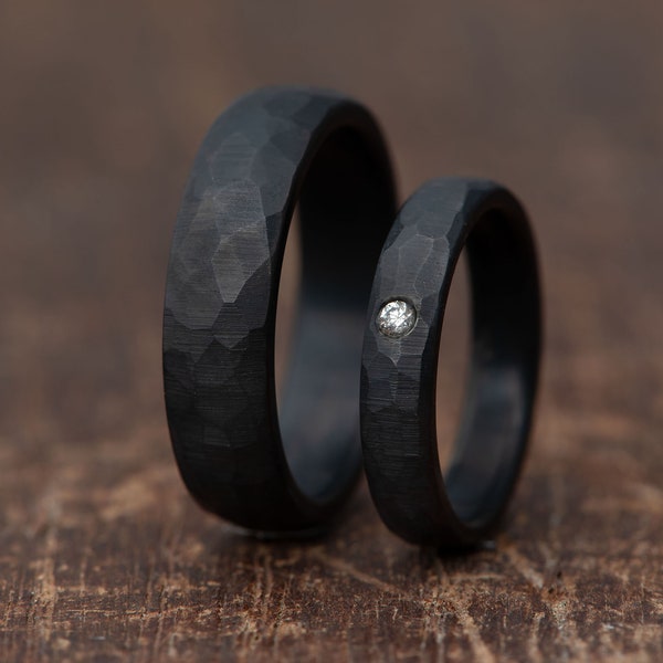 Set di anelli coordinati in titanio scuro con finitura in ossidiana sfaccettata e diamante autentico, finitura ruvida opaca. Semplice fede nuziale per lui e per lei.