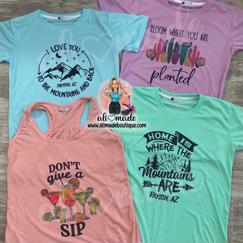 May include: Four t-shirts and a tank top in various colors: light blue, lavender, coral, and mint green. Each top features a graphic design with text. The light blue shirt says "I love you to the mountains and back." The coral tank top says "Don't give a sip."