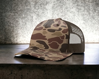 May include: A brown and tan camouflage trucker hat with a brown mesh back.