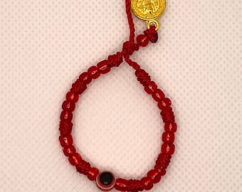 May include: Red string bracelet with a small gold charm and a blue evil eye bead.