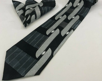 May include: A black and silver patterned tie and pocket square set. The tie has a geometric design with white circles and lines. The pocket square has a similar design.