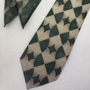 May include: A green and gold patterned tie and pocket square set. The tie and pocket square feature a geometric design with a repeating pattern of curved lines.