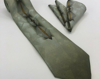 May include: A green patterned silk tie with a matching pocket square. The tie has a geometric design with brown and gold accents.