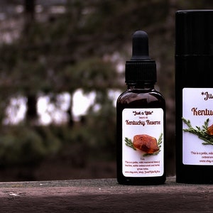 May include: Three bottles of beard oil and balm with the label "Just a Little" Kentucky Reserve. The bottles are on a wooden surface.