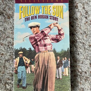 May include: A vintage VHS tape for the movie "Follow the Sun: The Ben Hogan Story." The cover features a man in a plaid shirt and khaki pants swinging a golf club. The background shows a golf course and other people.