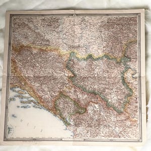May include: Antique map with detailed geographical features, including coastlines, rivers, and cities. The map has a vintage aesthetic with a color palette of brown, beige, and green. The map is folded and has a decorative border.