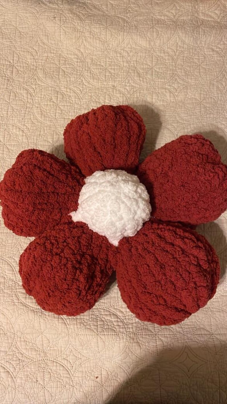 May include: A red and white flower-shaped pillow with a textured surface.