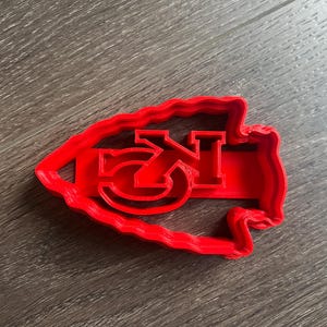 May include: Red plastic cookie cutter shaped like the state of Kansas with the letters "KC" inside.