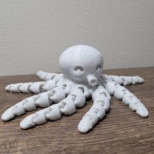 Pu&ograve; includere: Un polpo bianco stampato in 3D con una superficie testurizzata e otto tentacoli segmentati.