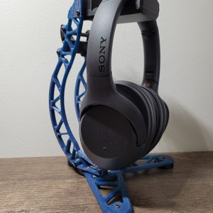 Pu&ograve; includere: Un supporto per cuffie stampato in 3D di colore blu con un paio di cuffie Sony nere appoggiate su di esso. Il supporto ha un design unico e intricato ed &egrave; realizzato in materiale plastico resistente.
