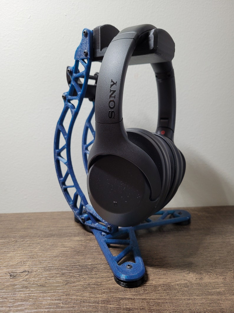 Pu&ograve; includere: Un supporto per cuffie stampato in 3D di colore blu con un paio di cuffie Sony nere appoggiate su di esso. Il supporto ha un design unico e intricato ed &egrave; realizzato in materiale plastico resistente.