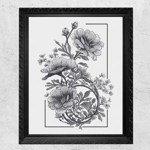 May include: Black framed floral art print. The artwork features a detailed black and white illustration of flowers and foliage, including roses and other blooms, arranged within a rectangular border. The frame has a decorative, textured edge.