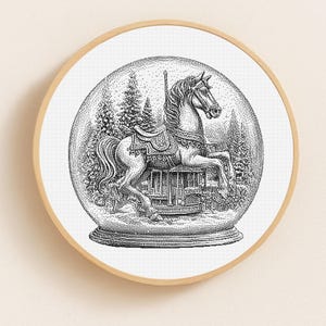 May include: Black and white illustration of a carousel horse inside a snow globe. The horse is detailed with a saddle and bridle, set against a backdrop of pine trees and a small building. The snow globe is framed in a round, light wood frame.
