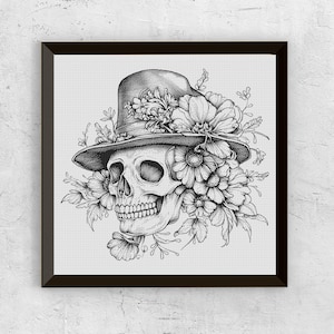 May include: A black and white dot art illustration of a skull wearing a hat decorated with flowers. The skull is shaded, and the flowers and hat are intricately drawn. The artwork is framed in a black square frame.