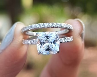 Könnte beinhalten: Ein silberner Ring mit einem großen, quadratischen, klaren Zirkonia-Stein. Der Ring ist mit kleineren Zirkonia-Steinen um die Band herum verziert.