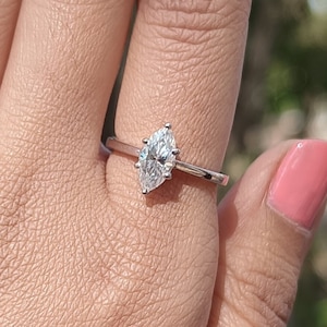 May include: A silver ring with a marquise-shaped diamond set in a prong setting.