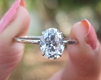 May include: A silver ring with a large, clear, round-cut diamond.