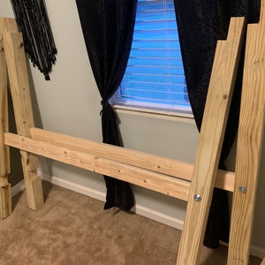 以下が含まれることがあります： 未完成の松の木材の板で作られたベッドのフレーム。フレームはネジで組み立てられており、マットレスを置く準備ができています。