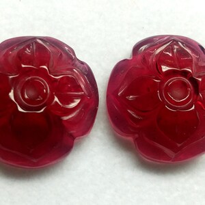 Op de afbeelding: Twee gegraveerde rode edelsteen bloem kralen. De kralen zijn gegraveerd met een vierbladig bloem ontwerp en hebben een gat in het midden om te rijgen.