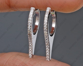 May include: A pair of silver hoop earrings with a row of small diamonds around the edge of each hoop.