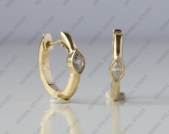 May include: A pair of gold hoop earrings with a small, clear marquise-shaped gemstone set in each hoop.