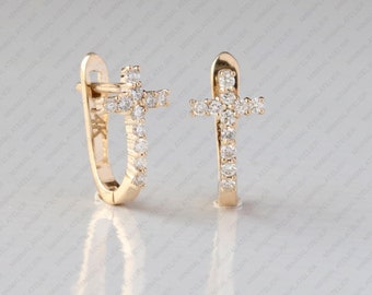 May include: A pair of gold hoop earrings with a cross design. Each cross is made of small, clear stones.