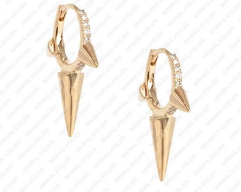 May include: Gold hoop earrings with a small, pointed spike hanging from each hoop. The hoops are decorated with a row of small, clear cubic zirconia stones.