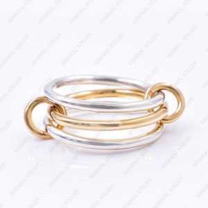 Puede incluir: Un anillo de oro y plata con múltiples bandas entrelazadas. El anillo está hecho de dos metales diferentes, creando un aspecto único y moderno.