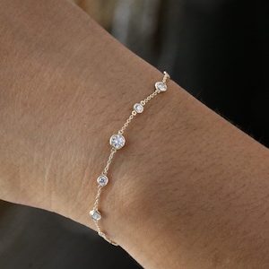 May include: A delicate gold chain bracelet with round, clear gemstones. The bracelet features a simple design with evenly spaced stones.